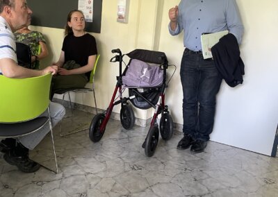 Ein Mann steht in einem Raum mit einem Kind und einer Gehhilfe.